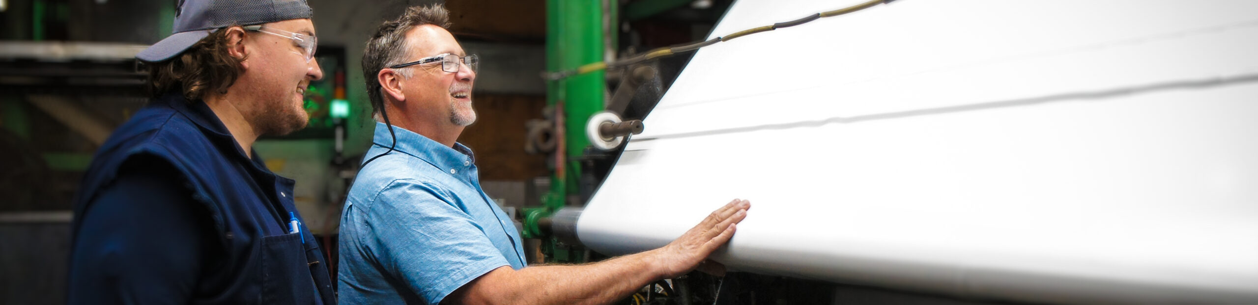 Two CGT Employees admiring materials next to the machine